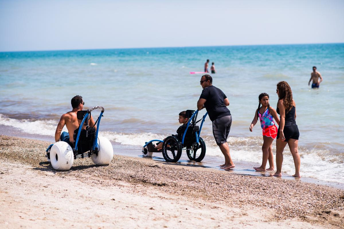 People use beach wheelchairs to enjoy the Lake Michigan on a sunny day