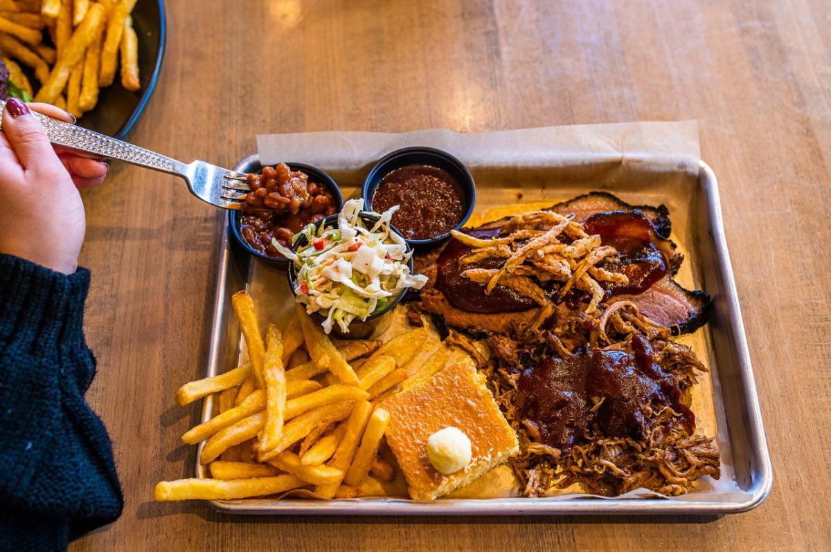 A tray of BBQ beef and brisket with a side of fries, cornbread, coleslaw and beans from MOTOR Bar & Restaurant
