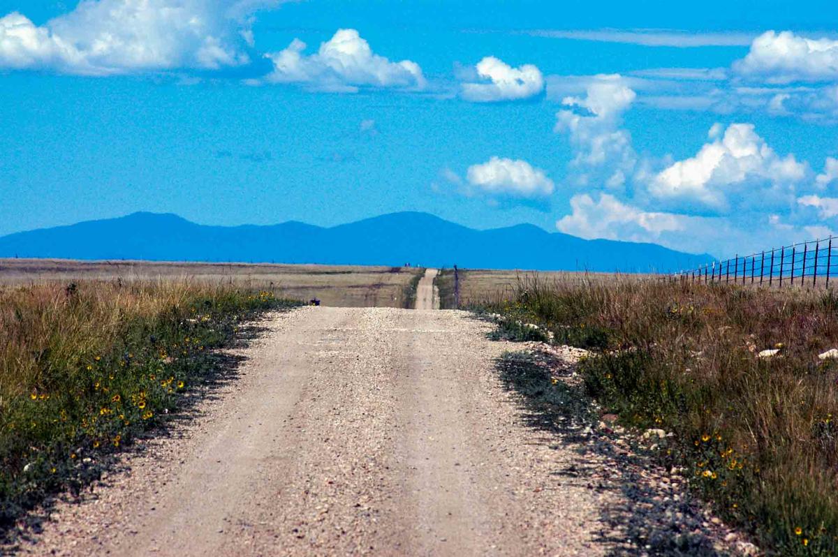 A gravel path winds into the horizon underneath blue skies
