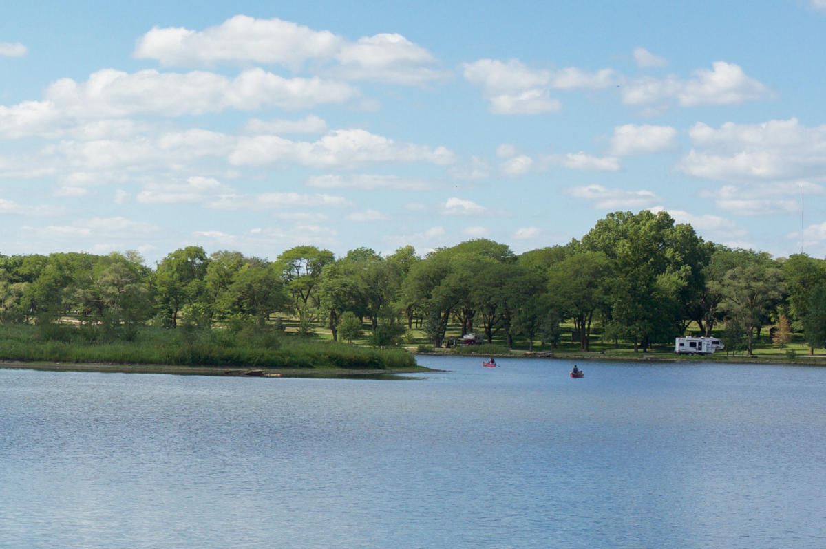 A scenic photo of Memphis Lake with people paddling in canoes.