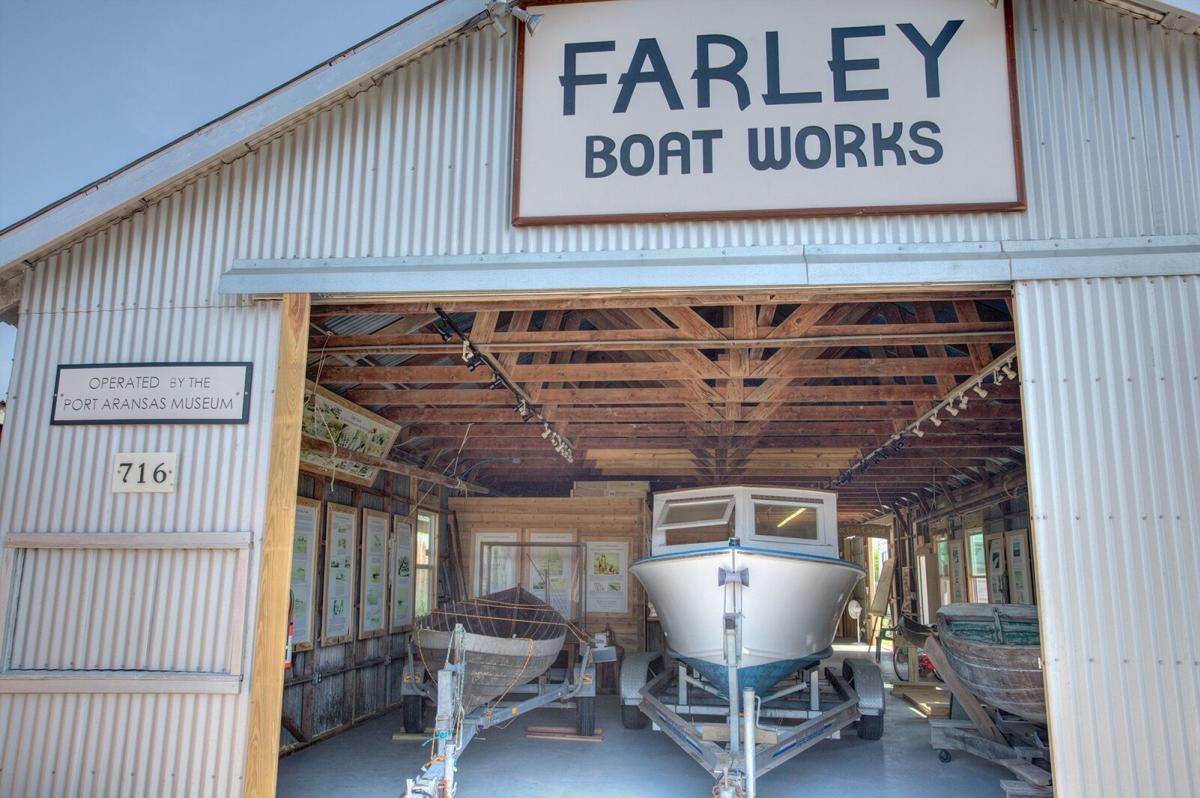 A white boat sits on a trailer inside a building with a sign reading "Farley Boat Works."