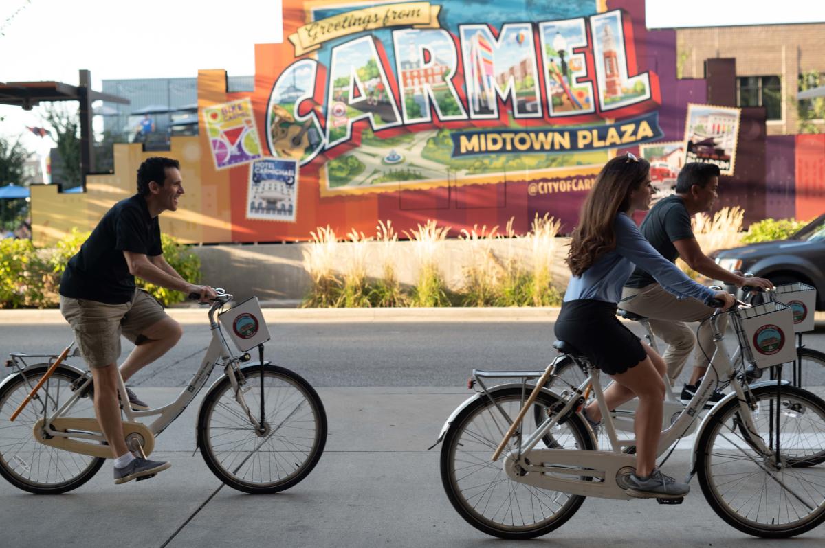 Hamilton County Tourism | Carmel - Midtown Plaza | people cycling in front of mural