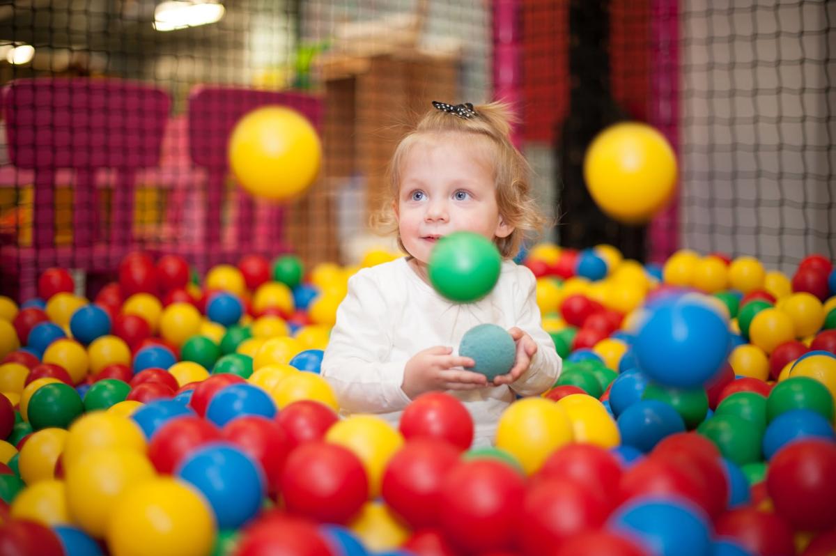Small child holding a ball in a ball pit at Wacky Kingdom