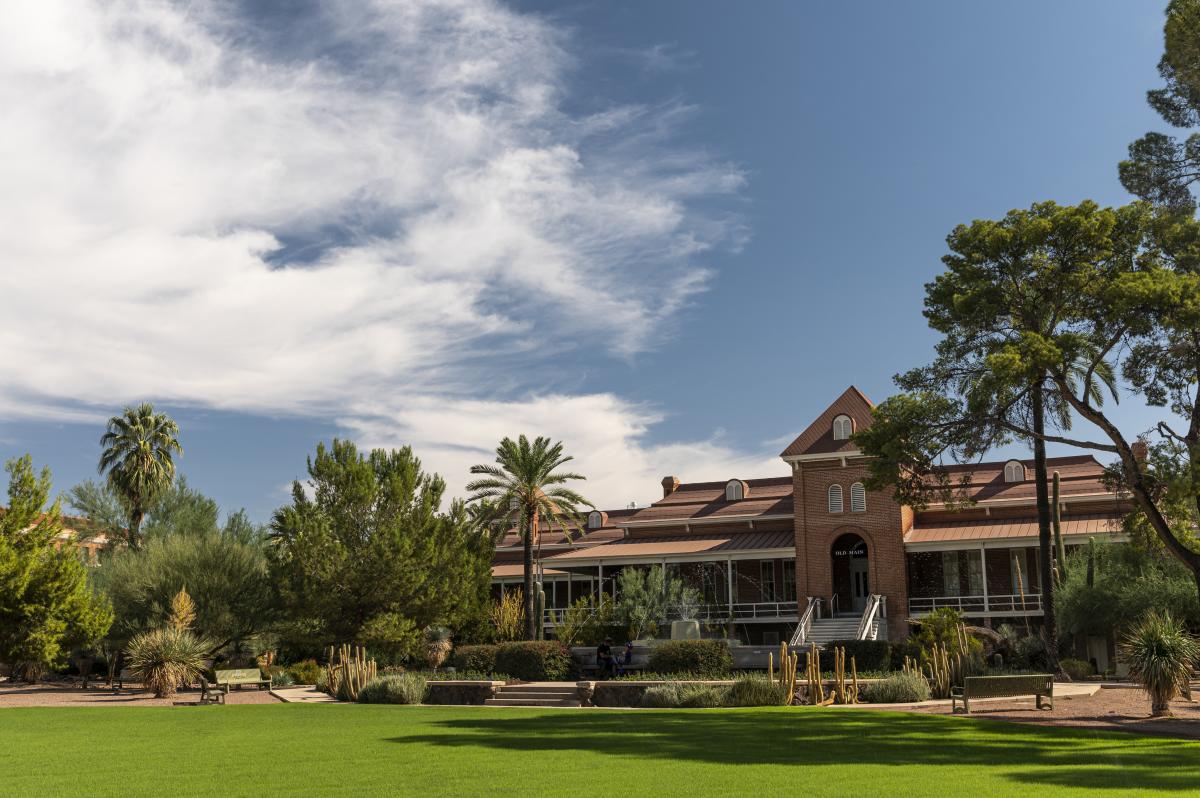 Exterior of University of Arizona's Old Main Building with a nicely landscaped grass, desert plants, and a fountain