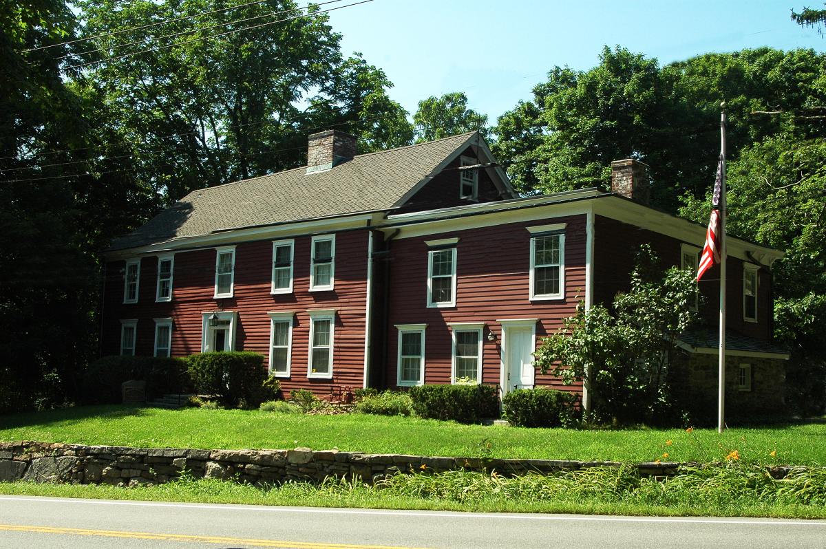 The exterior of the two-floor tavern with brown siding and a white door.