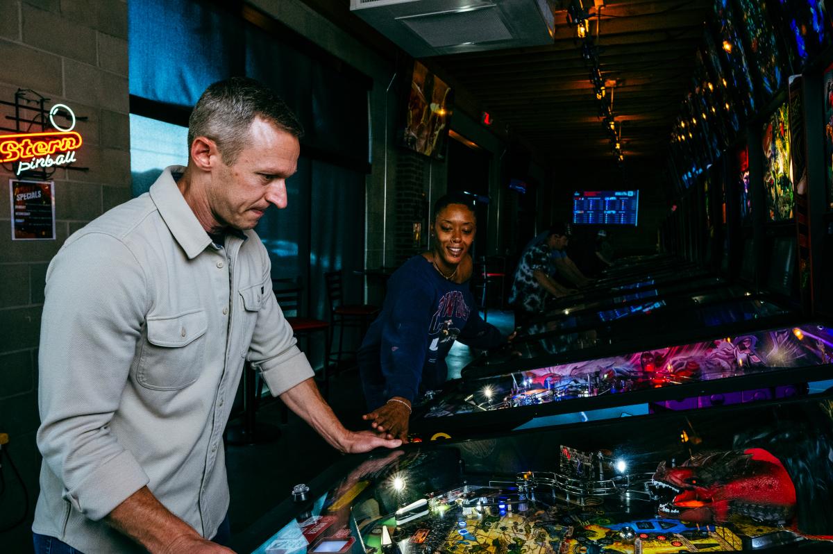 Two people play on a pinball machine at The Arcade in Wichita.