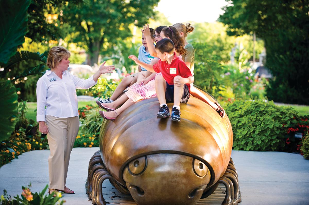 Kids sit on a bug statue while the Director of Education teaches them about the artwork at the Ulrich Museum of Art in Wichita