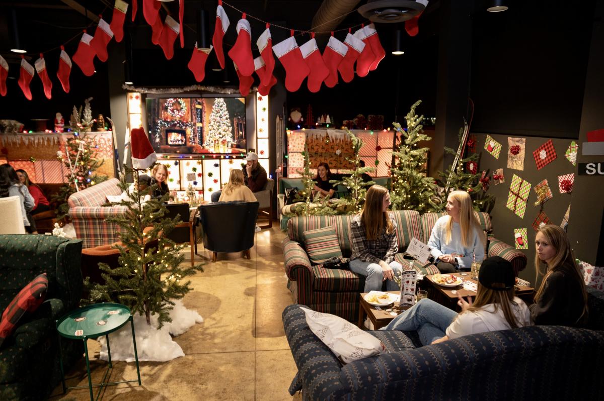 People enjoy cocktails seated on comfy couches inside the Holdiay Hideaway Pop-Up bar at Chicken N Pickle