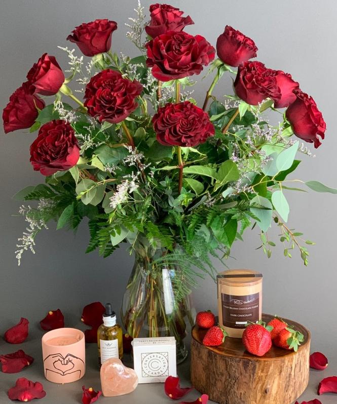 Red Roses in a vase with candle, chocolate and strawberries.