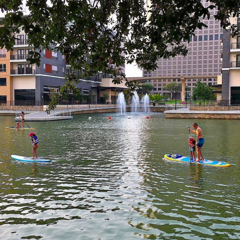 Man And Child Paddle Boarding On Lake Carolyn In Irving, TX