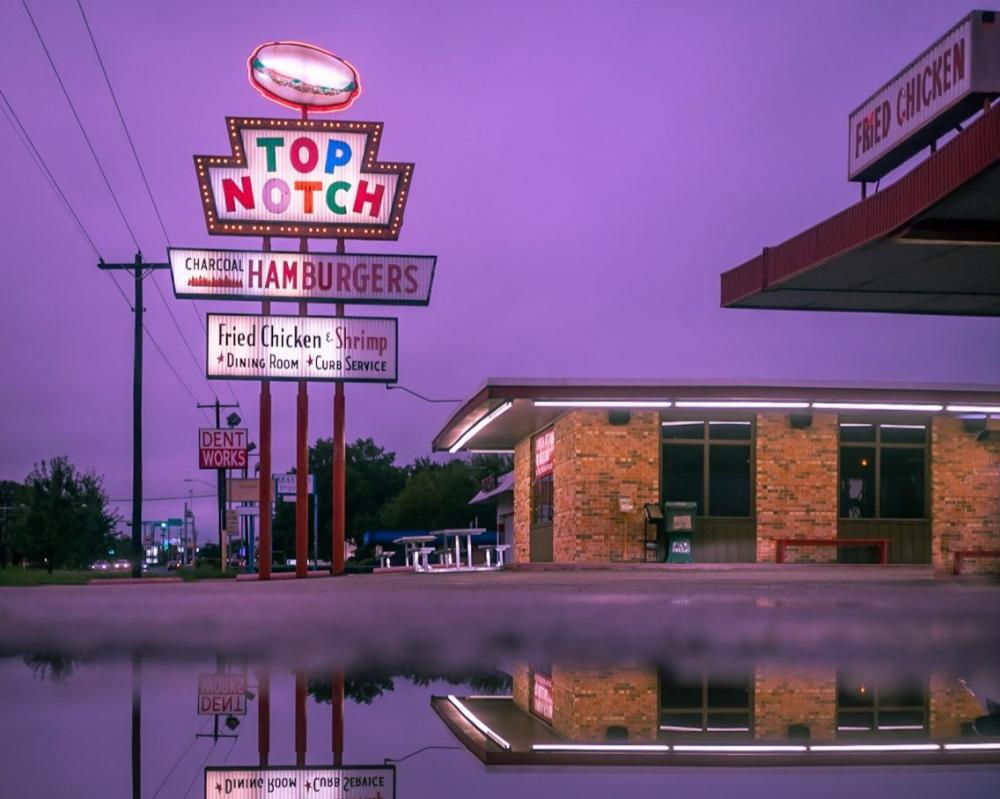 Moody shot of Top Notch Burger sign at night, juxtaposed on a dark purple sky.