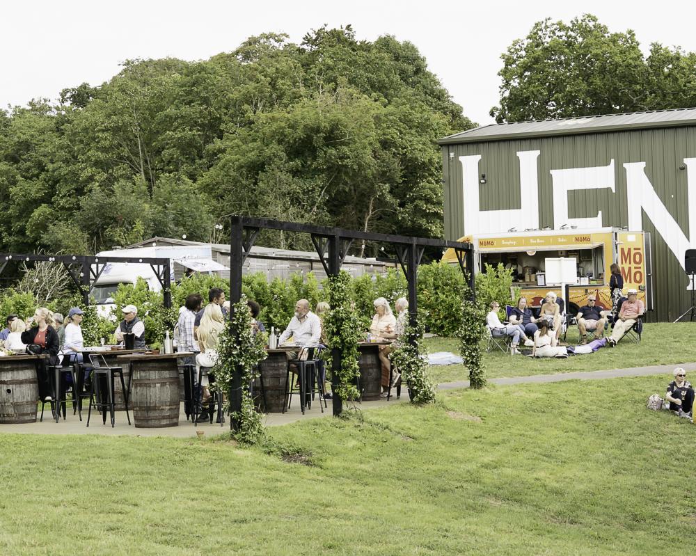 Henners vineyard with a large building in the background and people enjoying al fresco food and drink