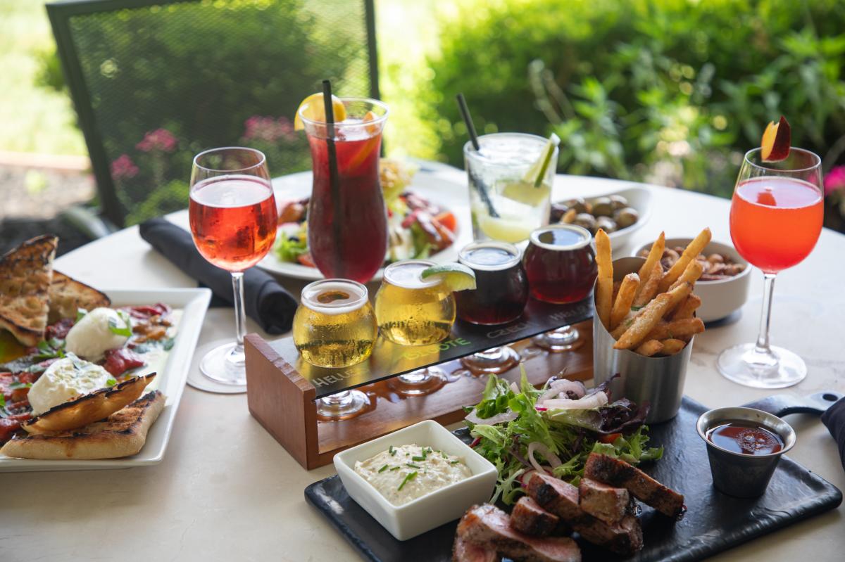 Image of a table with multiple different dishes, cocktails and beer at Old 290 Brewery & Restaurant.