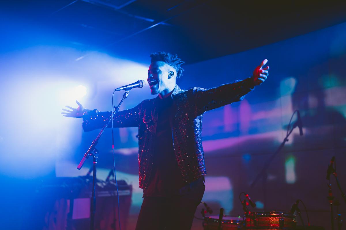 Man standing with arms open on a stage.