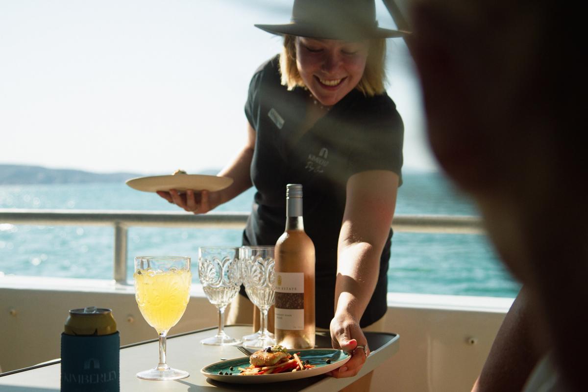 Guests onboard Kimberley Day Cruise being served some canapes and wine