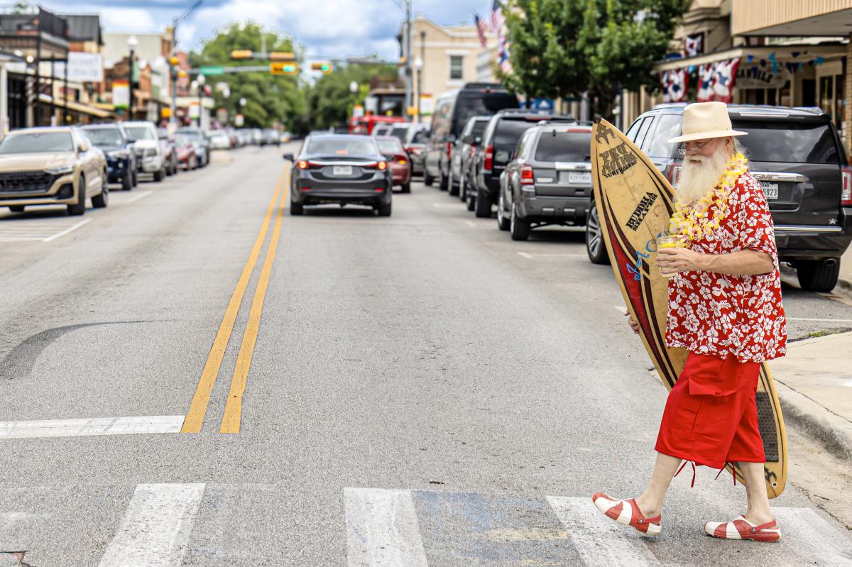 Santa Walking Across Main in summer wear and drinking a lemonade