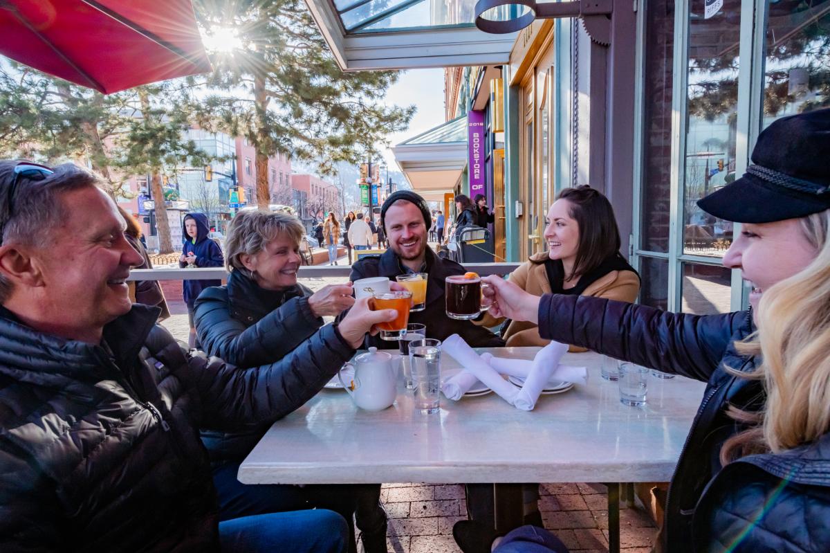 A family cheers with smiles and laughter at a Pearl Street patio restaurant in Boulder, CO.