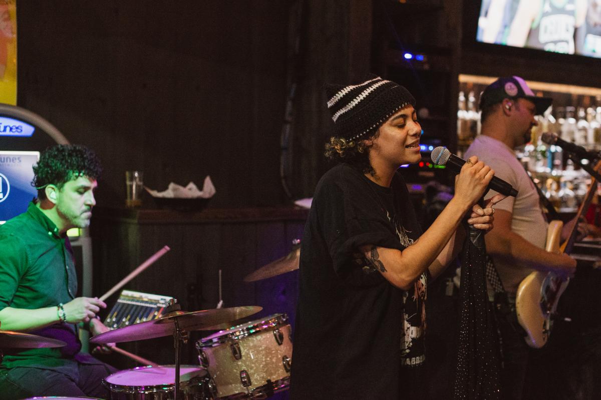 a singer signing a song at a mic and backed up by a live band