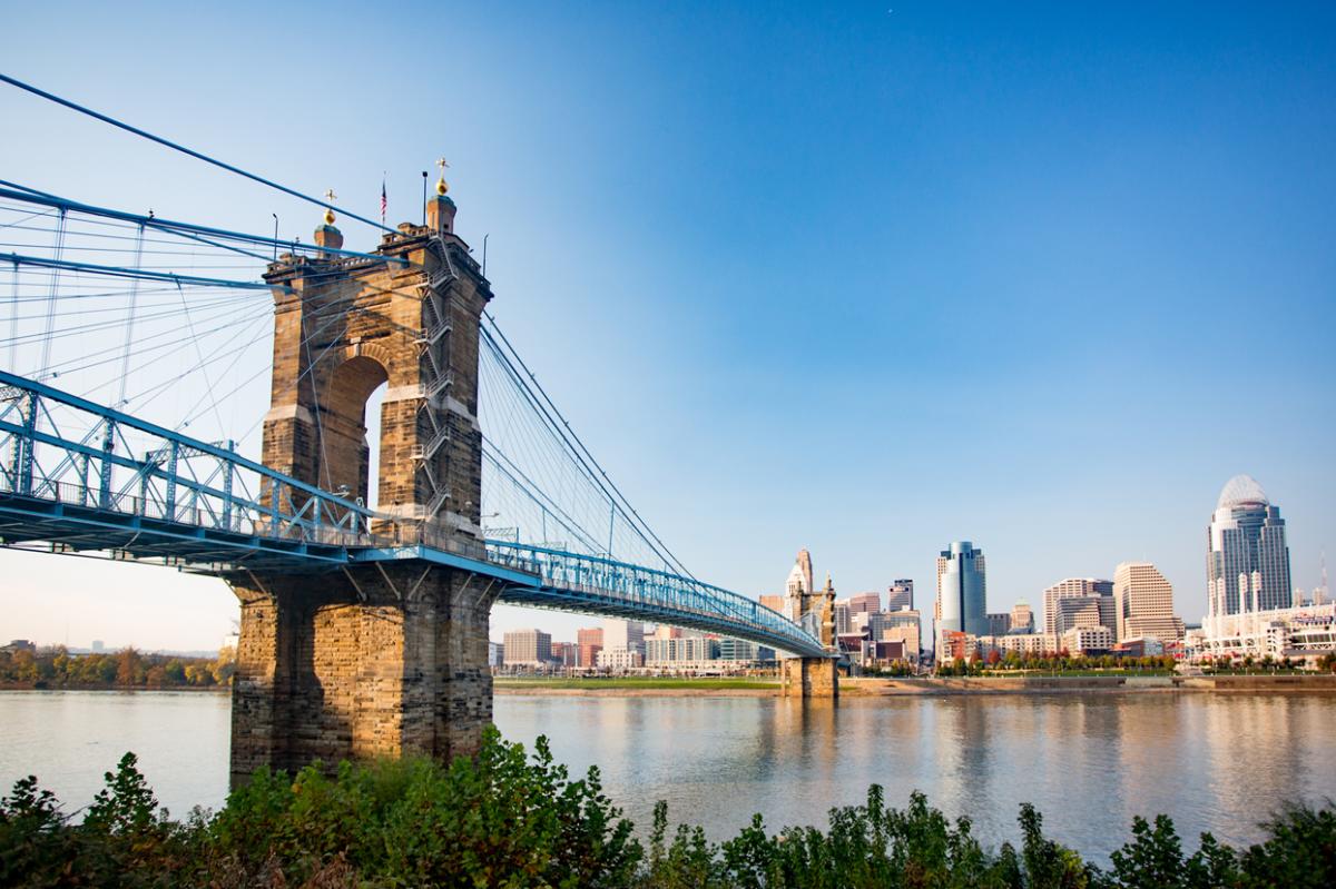 The Roebling Suspension bridge leading to downtown Cincinnati's skyline under a sunny blue sky