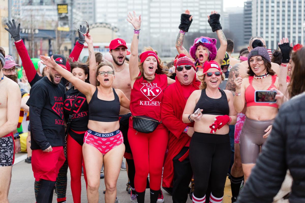Image is of a group of people posing for a photo wearing red underwear and running gear.