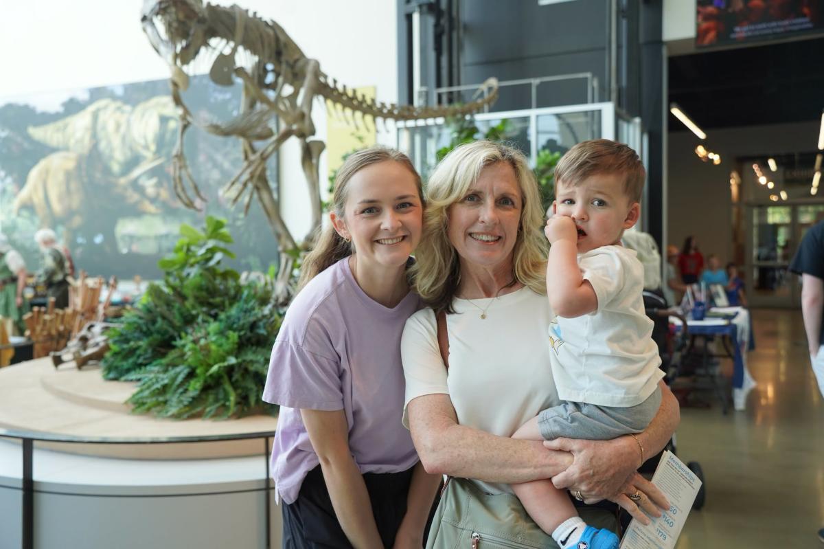 Family poses in front of dinosaur skeleton.