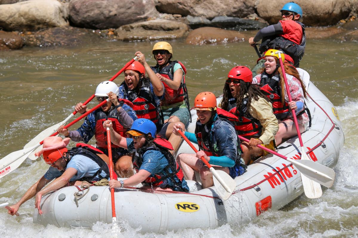 A large raft full of rafters going over a rapid.
