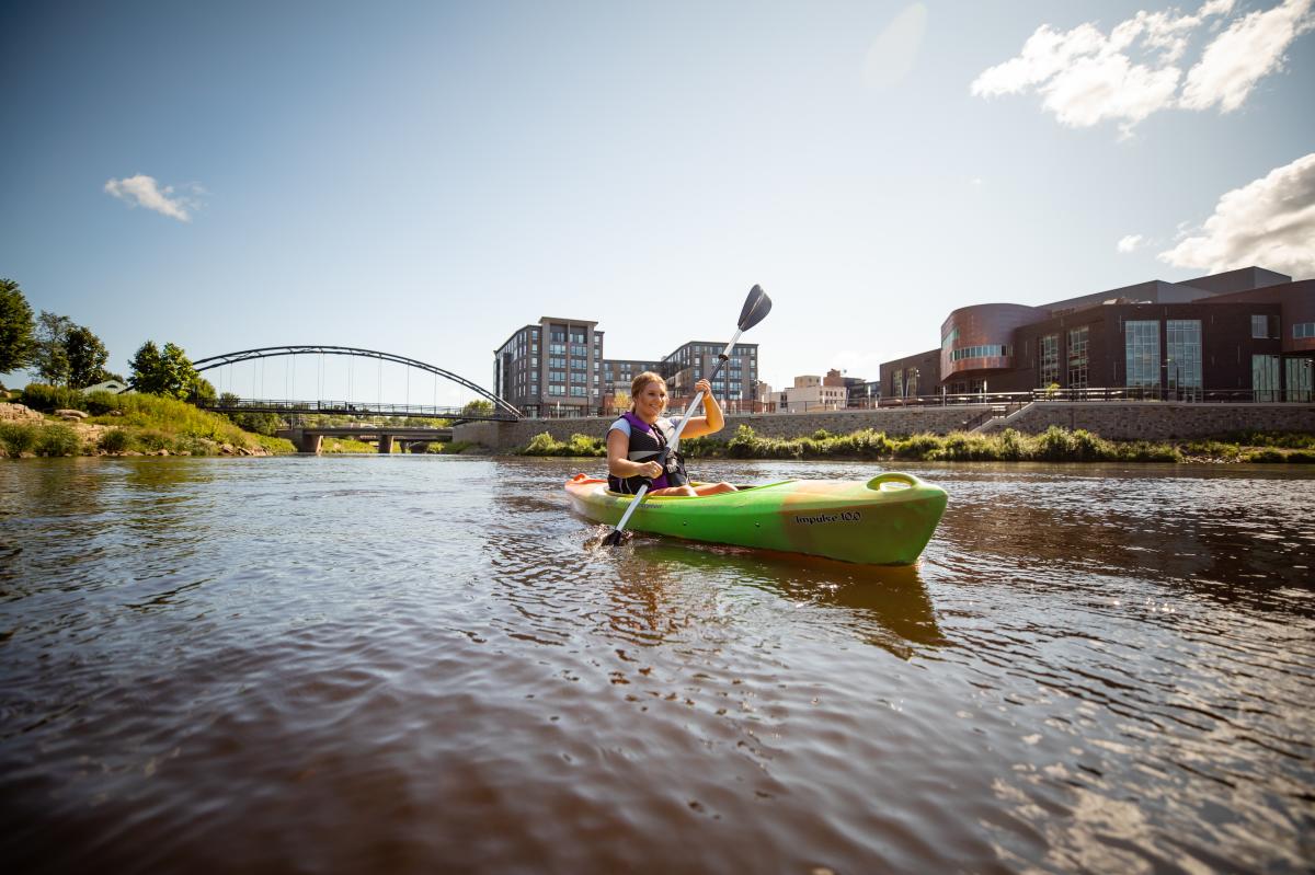 A kayaker in the Chippewa River in front of Haymarket Plaza