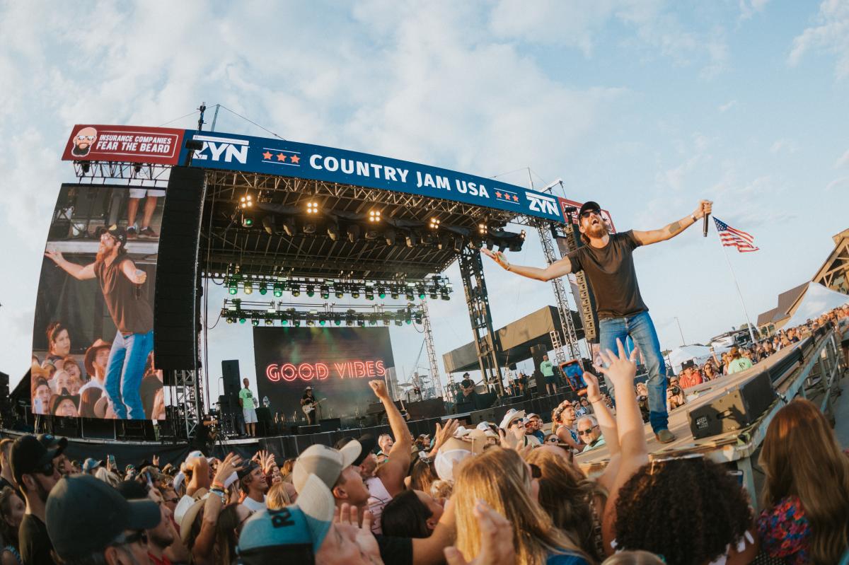 A country singer on stage performing in front of a crowd at Country Jam