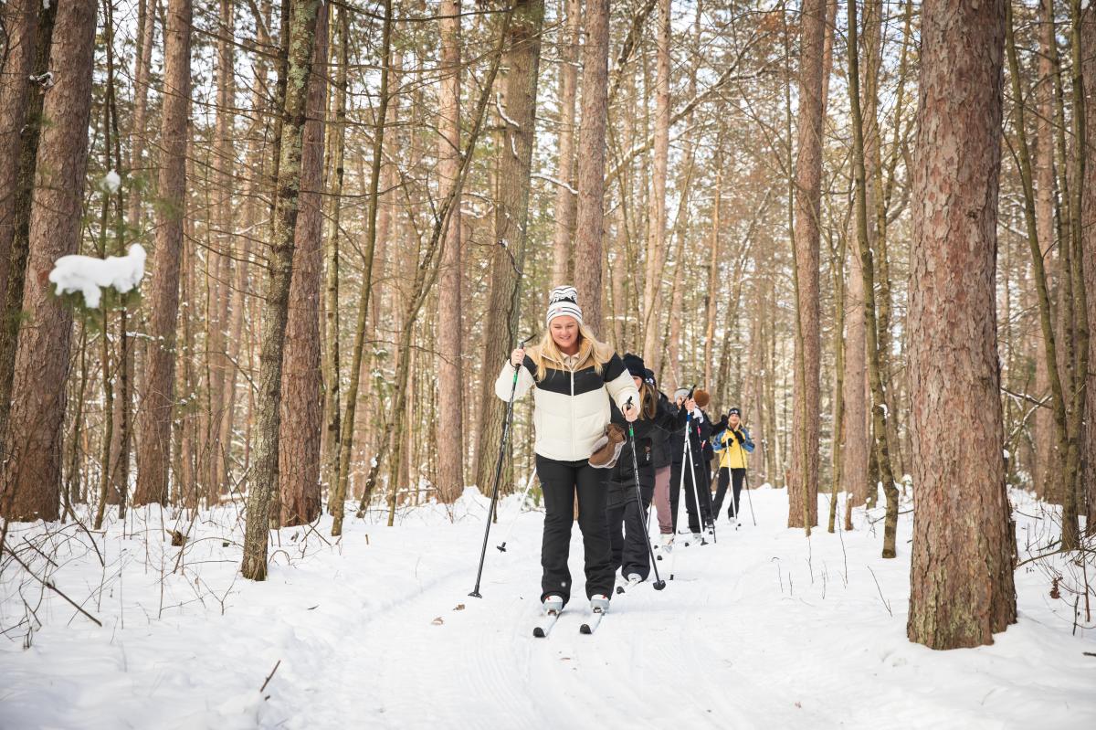 A large group of people cross country skiing in the winter at Beaver Creek Reserve in Fall Creek, WI