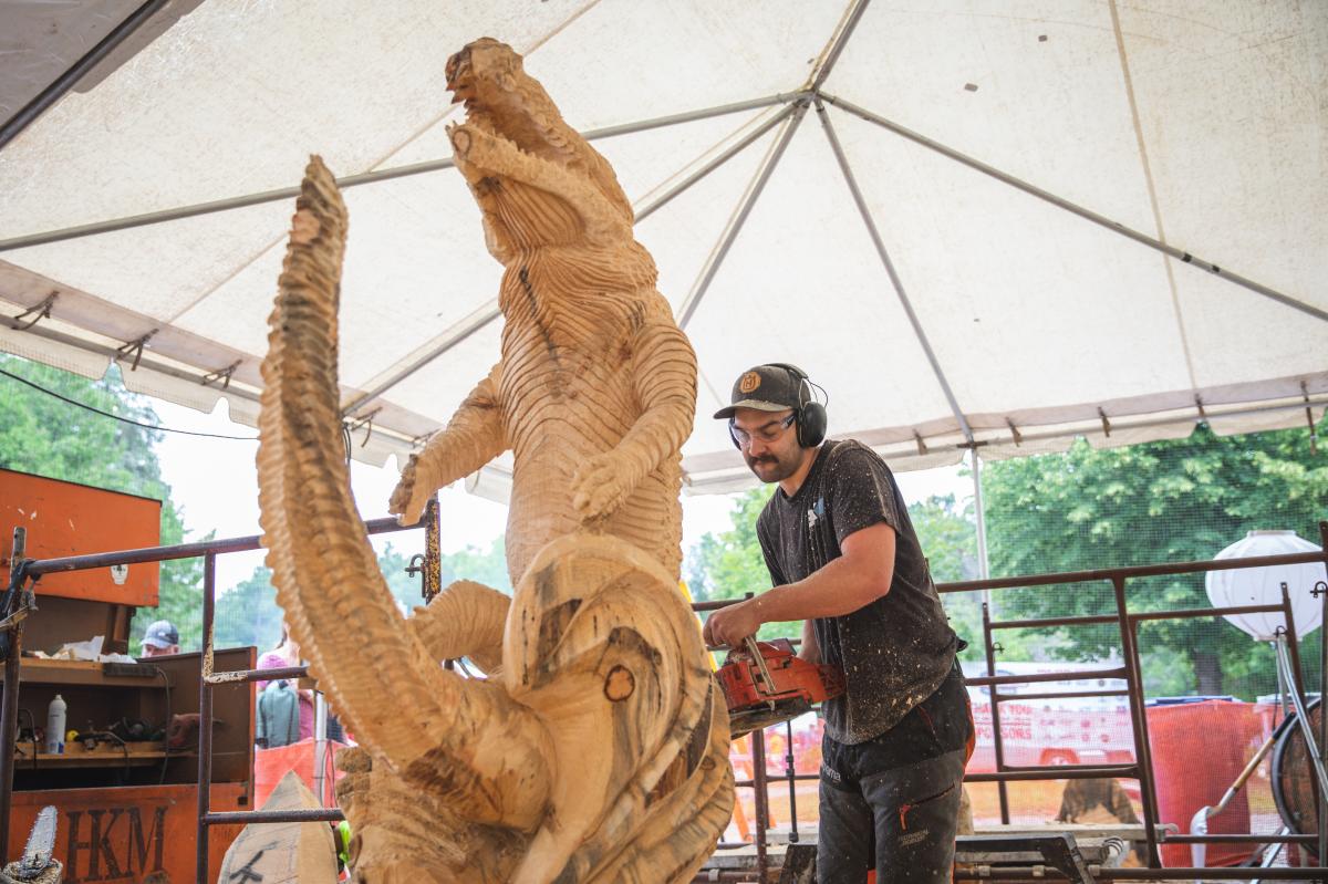 A man carving a sculpture out of wood at the 2022 US Chainsaw Sculpture Championships in Eau Claire, WI