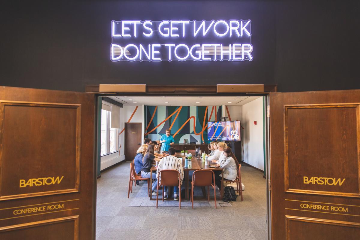 a group of people gathered at a meeting table with laptops at CoLab in Eau Claire