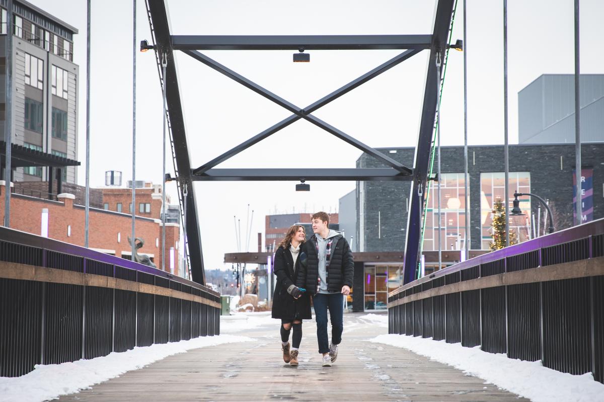 A couple walking hand in hand on the Haymarket Plaza bridge in the winter