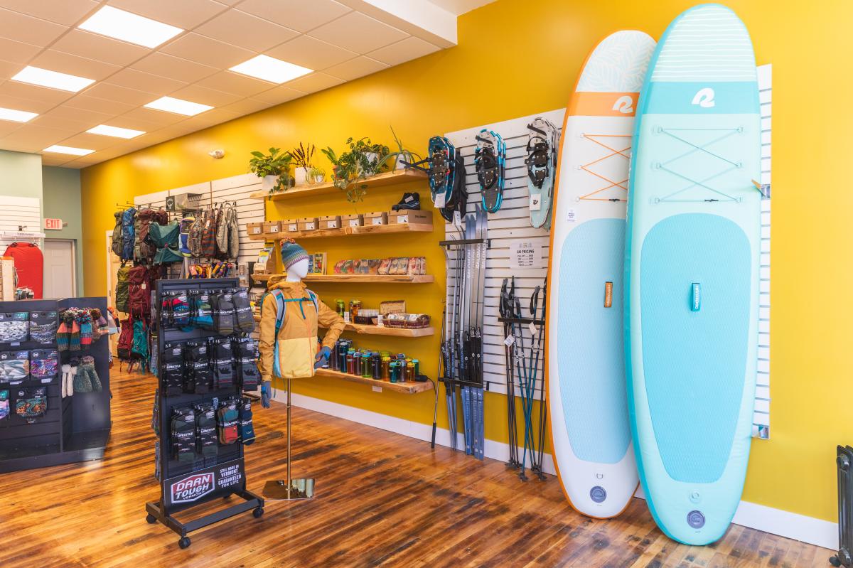 a photo inside Eau Claire outdoors showing the bright walls, paddle boards, snowshoes, shoes, and more outdoor gear