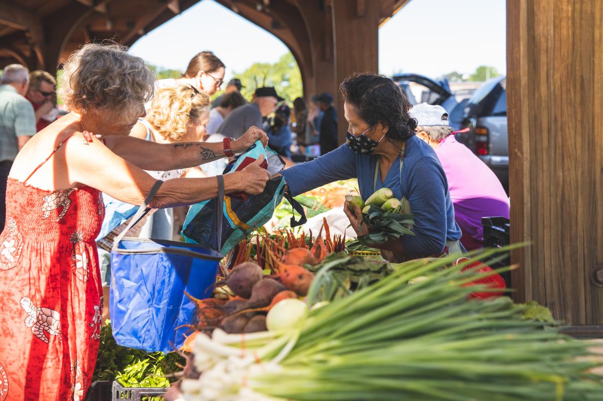 A woman buying fresh local produce from the downtown Eau Claire Farmers Market