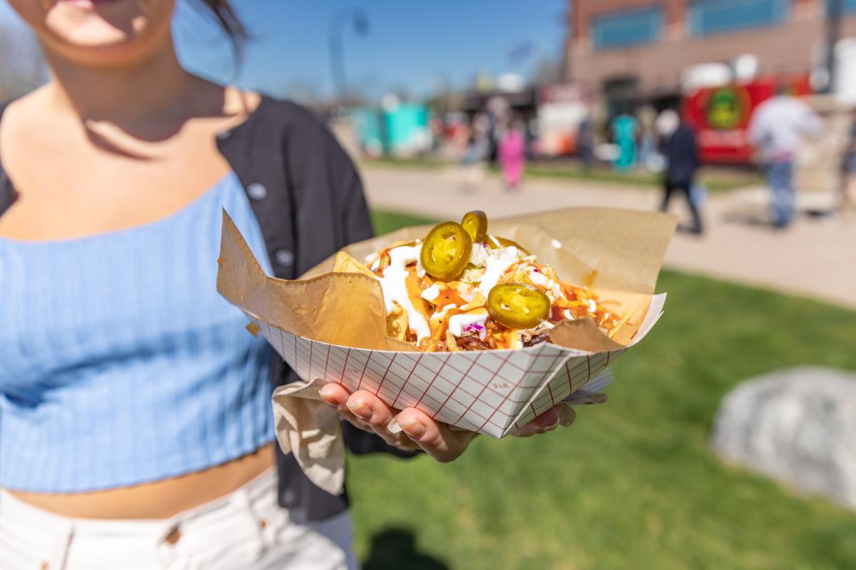 A girl holding a boat of bbq nachos