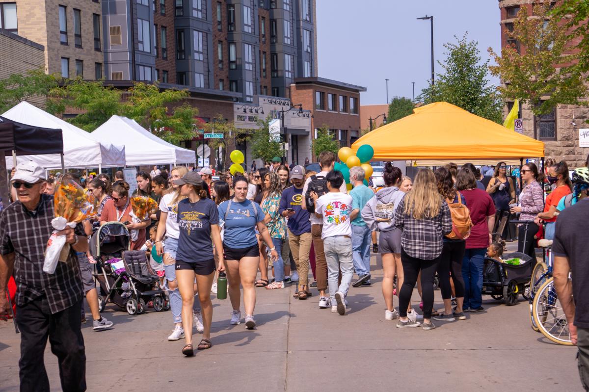 Crowd of people walking by vendor tents in downtown Eau Claire