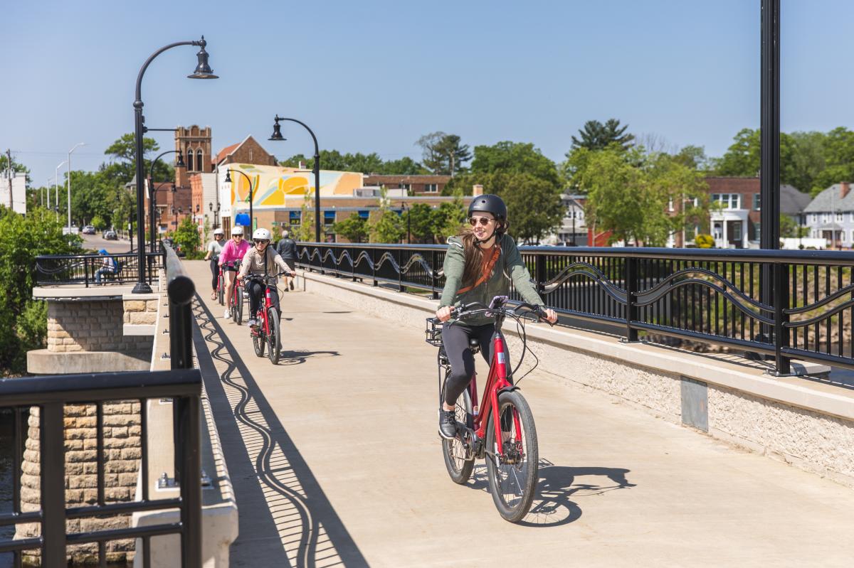 A group of women riding e-bikes on a bridge in downtown Eau Claire