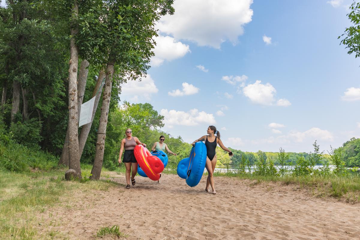 3 girls carrying river rubes through the sand by the Chippewa River at Loopy's Saloon & Grill