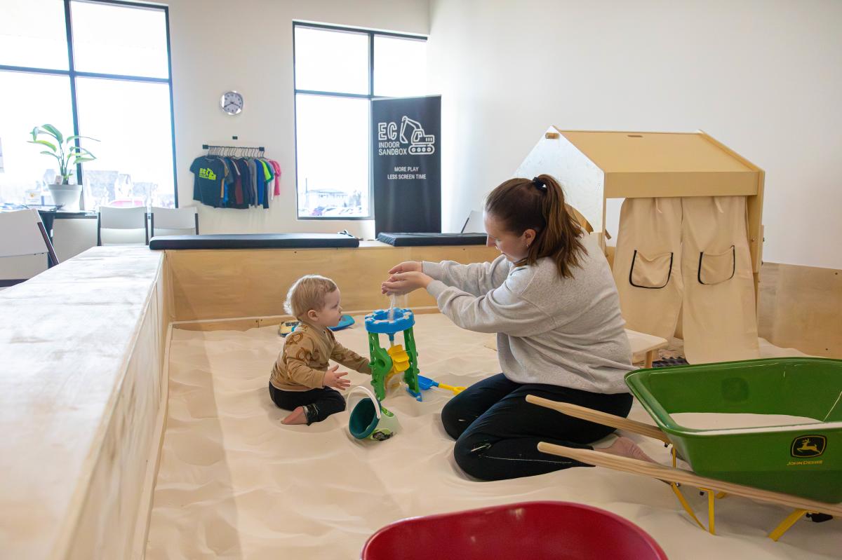 A mom and son playing in the indoor sandbox
