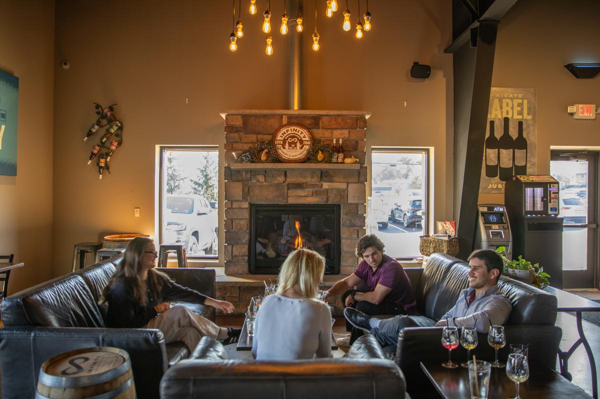 A group of people sitting near a fireplace drinking cocktails at Infinity Beverages
