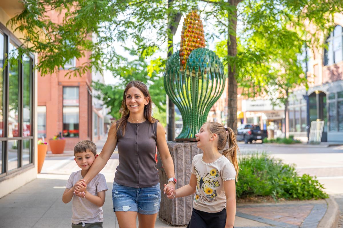 A mom walking with her two kids near a sculpture