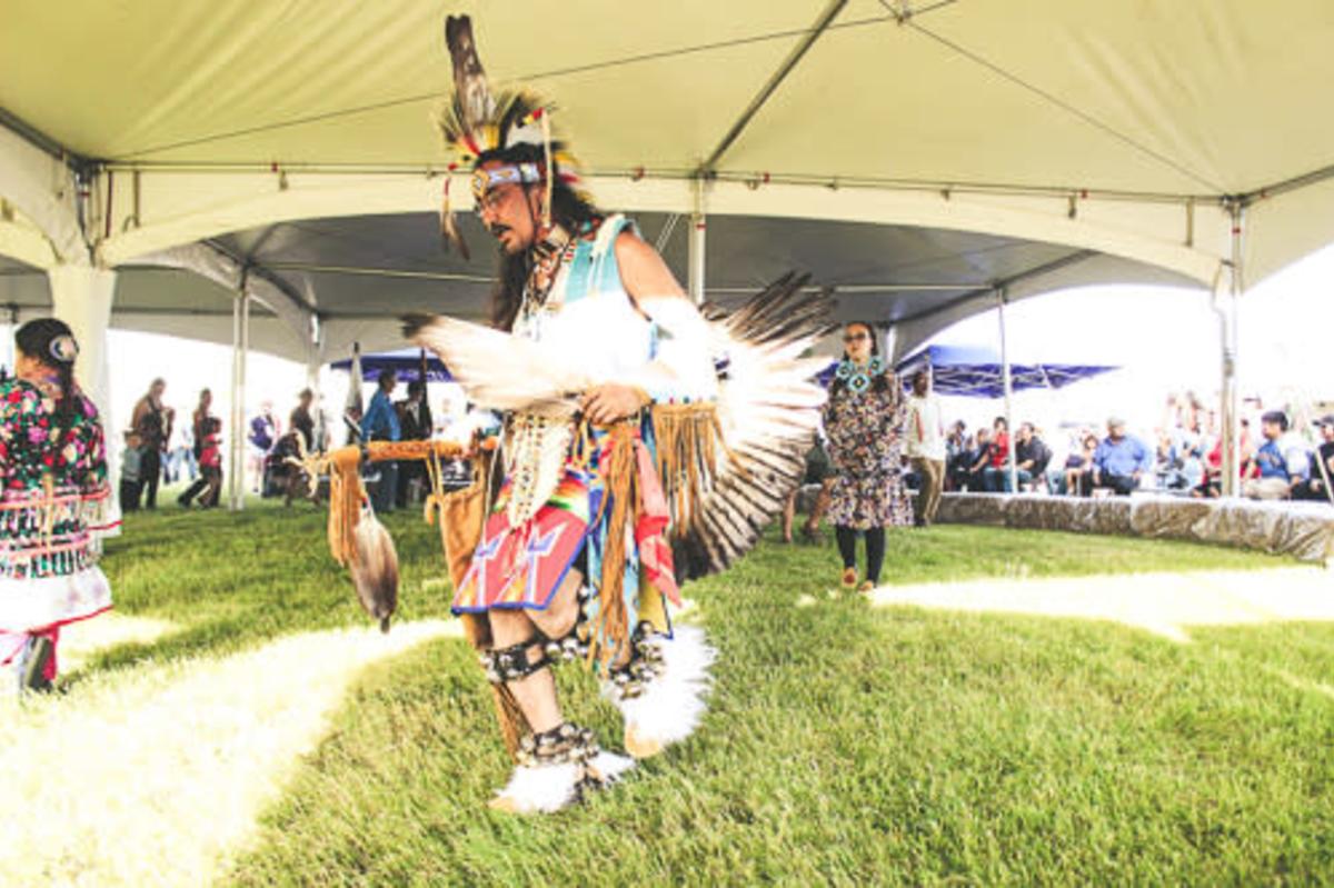 Person participating at the Midnight Sun Intertribal Powwow in Fairbanks, wearing regalia and standing among attendees during the gathering.