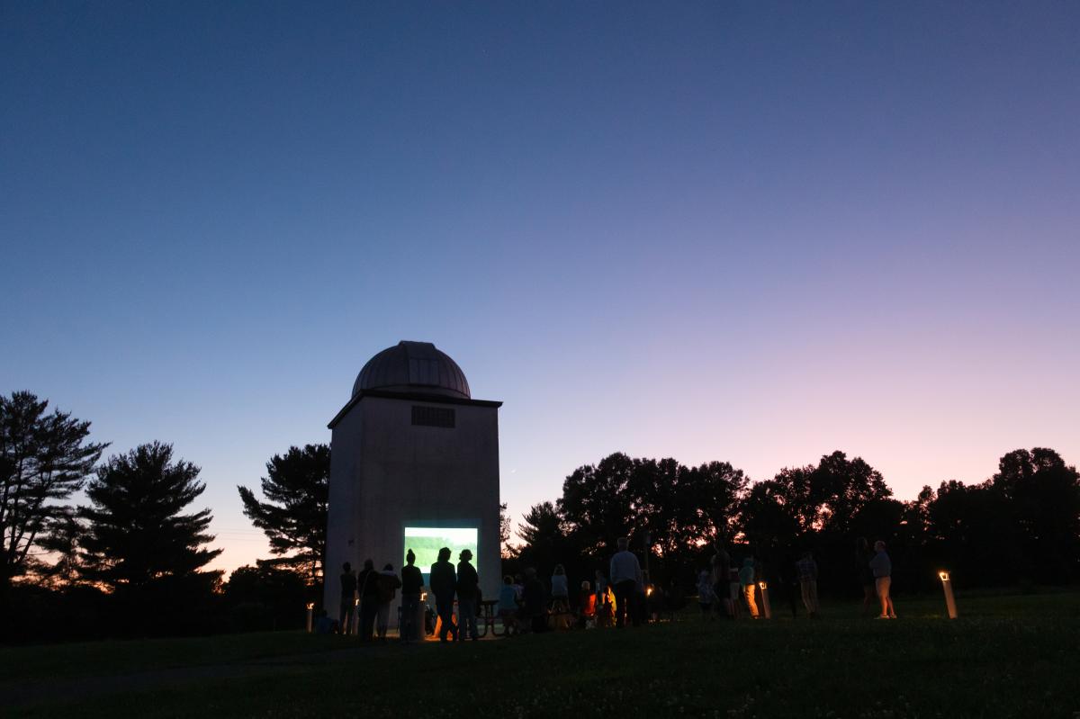 Roll-Top Observatory with a crowd looking at the projector screen during sunset.