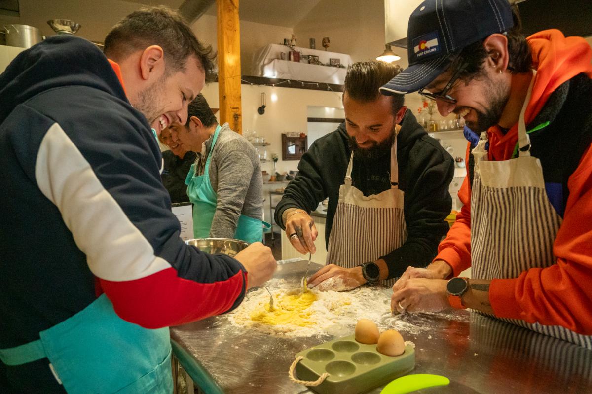 A group of people working together to make pasta dough with eggs.