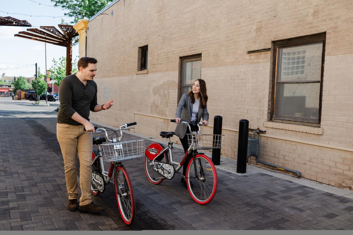A couple walking two bikes through an alley
