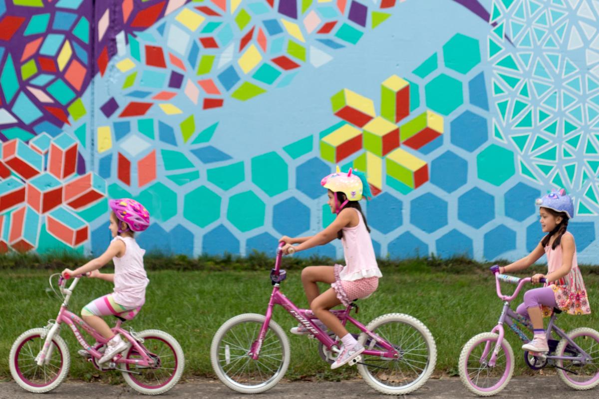 Girls biking by mural