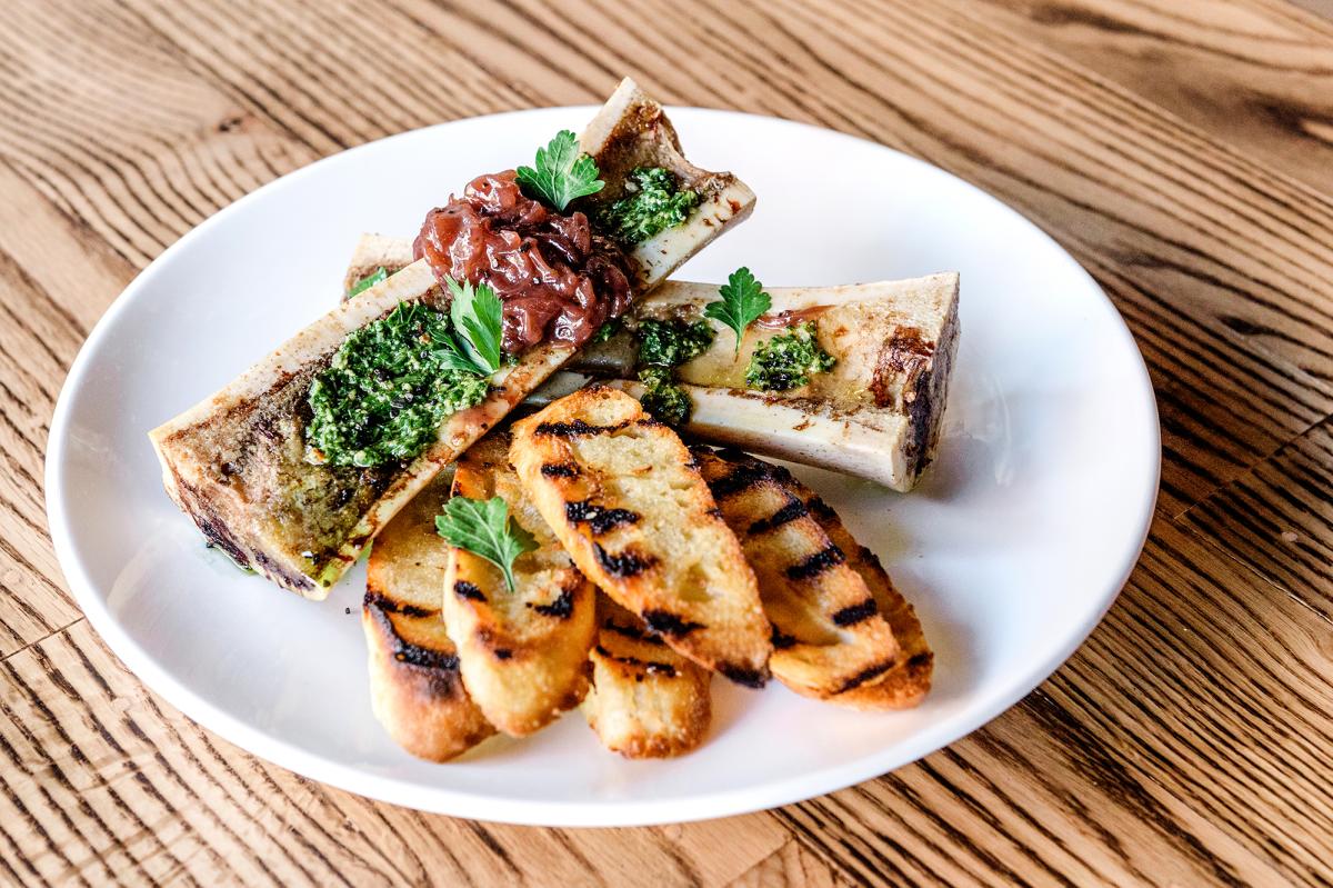 Bone marrow at Tolon restaurant on a white plate on a wood table.