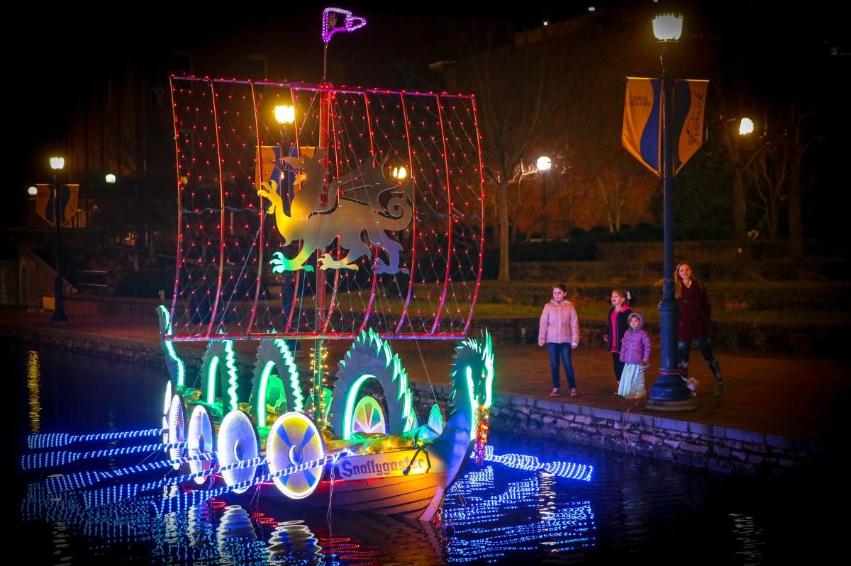 Family watching lighted boats at the Sailing Through The Winter Solstice event