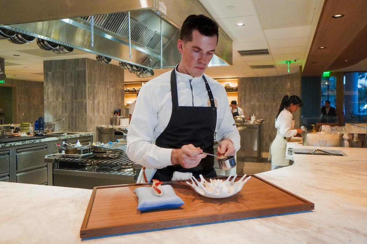 A chef putting the finishing garnishes on a plate.
