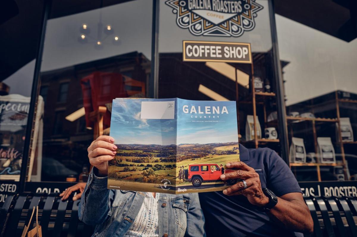 Two people sitting on a bench, holding a visitors guide.